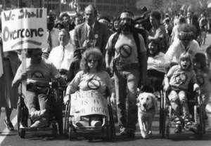 Old school disability rights protest – signs read “we shall overcome” and “access is a civil right” – photo by Tom Olin