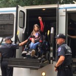 ADAPT member Dawn Russell raises her first in power as she is loaded on to a police vehicle